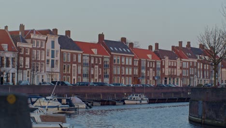 a-beautiful-cinematic-view-of-european-street-in-Netherlands-Holland-with-houses,-water-canal,-boats-and-authentic-dutch-style-town-city-archuitecture-with-sunset-and-sunlight