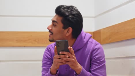 Happy-Asian-man-talking-and-using-smartphone,-front-view