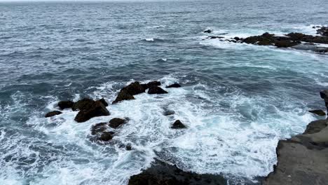 Waves-crashing-on-the-rocky-shoreline-of-Iceland,-overcast-sky,-tranquil-yet-powerful-nature-scene