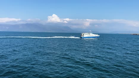 Blue-ferry-crossing-the-Icelandic-waters-with-mountains-under-a-clear-sky,-daytime,-medium-shot