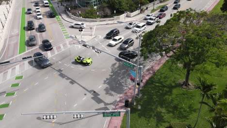 Miami-Florida-USA,-Aerial-View-of-Slingshot-Vehicle-on-Road-Intersection-With-Regular-Cars-on-Sunny-Day,-Drone-Shot
