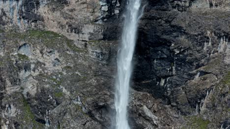 Mountain-waterfall-flowing-into-alpine-lake,-lush-greenery-surrounds,-daylight,-tranquil-nature-scene