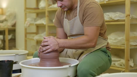 Potter-shaping-clay-spinning-on-pottery-wheel-in-studio-small-business-workshop