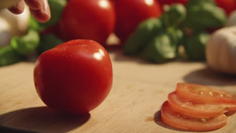 Close-up-of-chefs-knife-cutting-tomato-cleanly-in-two-halfs-along-fingertips