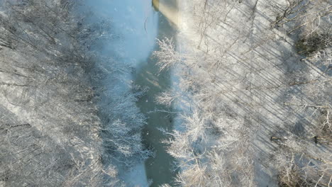 Magical-winter-snow-covered-white-landscape,-bird's-eye-view-of-frozen-creek