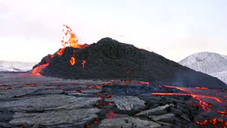 Eine-4K-Drohne-Macht-Filmreife-Luftaufnahmen-Von-Einem-Vulkan,-Der-Schnell-Lava-Ausstößt,-Gefolgt-Von-Einem-Zeitlupen-Abfluss-Am-Fuße-Des-Gipfels-In-Island