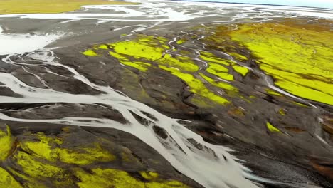 Aerial-cinematic-shots-from-a-4K-drone-showcase-Iceland's-distinctive-landscape,-featuring-ice-formations-resembling-tree-roots-or-veins-juxtaposed-with-lush-green-grassy-terrain