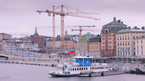 Aerial-view-of-construction-cranes-next-to-Slussbron,-Gamla-Stan,-Stockholm
