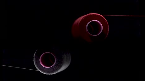 two-thread-on-spool-bobbin-red-purple-unwind-slow-motion-high-angle-static