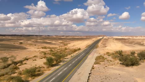 Car-zooming-by-heading-north-on-a-Desert-highway-with-cloudy-blue-sky