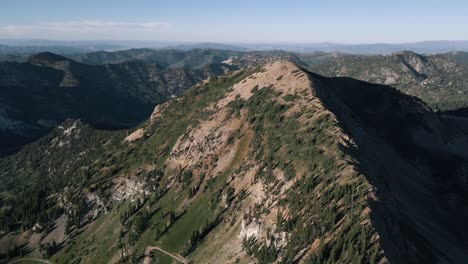 Ascending-aerial-view-to-the-top-of-a-mountain-ridge-in-Utah-near-Snowbird-Ski-Resort-on-a-sunny-summer-day