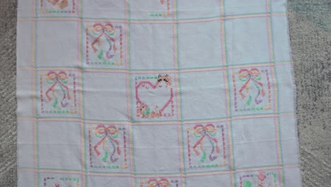 Slow-pullout-revealing-shot-of-a-cross-stitched-baby-blanket-on-the-ground