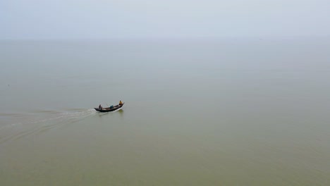 Two-men-ride-a-fishing-trawler-boat-out-onto-the-Indian-Ocean,-going-fishing-in-the-Bay-of-Bengal,-Bangladesh