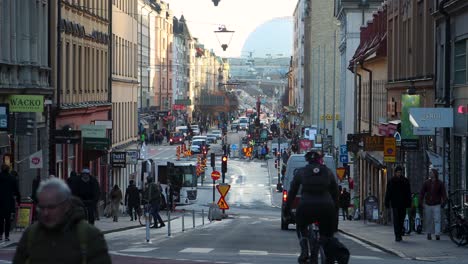 People-ride-bikes-and-walk-on-street-Gotgatan-in-Stockholm,-static