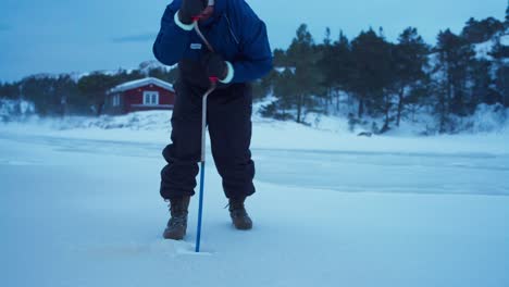 Ein-Mann-Bohrt-Mit-Einem-Eisbohrer-Manuell-Ein-Loch-Ins-Eis-Zum-Angeln-In-Bessaker,-Provinz-Trondelag,-Norwegen-–-Statische-Aufnahme