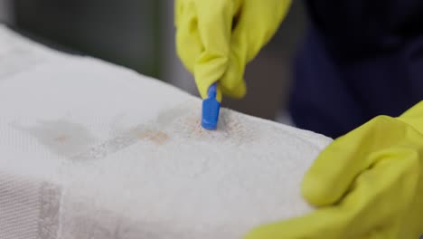 Hands-In-Gloves-Removing-Stain-On-White-Towel-Using-Brush-At-Laundry-Shop