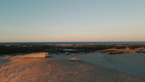 Aerial-flyover-establishing-shot-of-tourists-exploring-the-Provincetown-Dunes