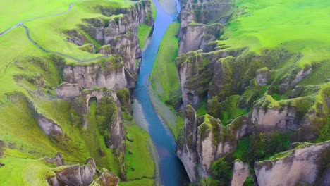 A-4K-drone-captures-a-breathtaking-cinematic-aerial-view,-showcasing-the-distinctive-landscape-of-a-lush-green-canyon-nestled-along-the-southern-coast-of-Iceland