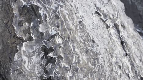 Water-flows-over-a-rock-and-melting-clear-ice