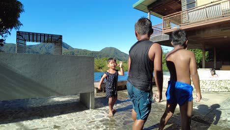 Dos-Niños-Saltando-A-La-Piscina-De-Una-Casa-De-Vacaciones-Con-Fondo-Montañoso,-Dinámico