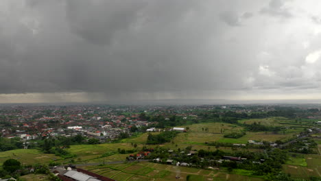 Luftbild-Rückflug-über-Reisfelder-Auf-Bali-In-Indonesien-Mit-Bewölktem,-Stürmischem-Himmel