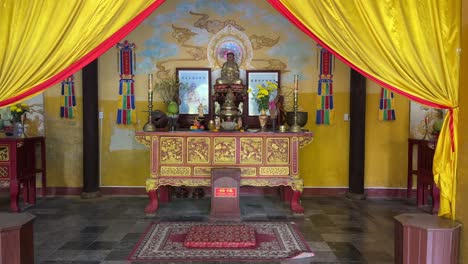 Santuario-Dentro-Del-Templo-Budista-Guan-Di-En-Hoi-An,-Vietnam-Con-Cortinas-Amarillas-Echadas-Hacia-Atrás