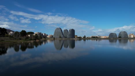 Spiegelt-Die-Architektur-Tiranas-Wider:-Die-Skyline-Der-Stadt-Und-Der-Blaue-Himmel-Spiegeln-Sich-Im-Ruhigen-Wasser-Des-Künstlichen-Sees-Und-Umfassen-Das-Stadtdesign