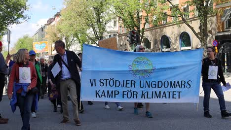 Elderly-protesters-march-for-climate-with-banner-in-Stockholm,-Sweden