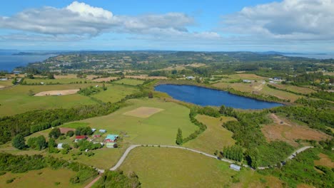 Lemuy-island-in-chiloé-archipelago,-showcasing-vibrant-landscapes,-a-serene-lake,-and-scattered-homes,-aerial-view