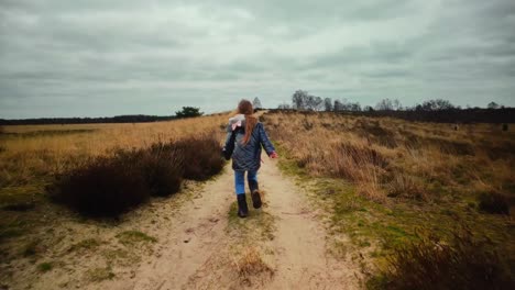 Blondes-Kind-Läuft-In-Zeitlupe-Einen-Weg-In-Der-Wintersanddünenlandschaft-Hinauf