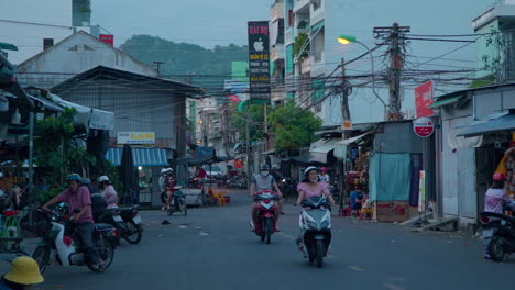 Einheimische-Vietnamesen-Aus-Nha-Trang-Fahren-Am-Frühen-Abend-Auf-Motorrädern-In-Einem-Kleinen-Alten-Viertel-Vorbei,-Vietnam---Zeitlupe