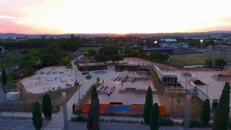 Aerial-orbiting-shot-of-skaters-using-the-newly-constructed-skatepark-at-sunset