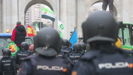 Police-officers-stand-guard-as-Spanish-farmers-and-agricultural-unions-gather-at-Plaza-de-la-Independencia-to-protest-against-unfair-competition,-agricultural-and-government-policies