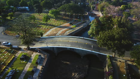 Aerial-view-over-traffic-and-people-on-a-bridge-in-Manila-memorial-park,-Philippines