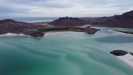 Playa-balandra's-clear-turquoise-waters-and-surrounding-mountains-in-baja-california,-aerial-view