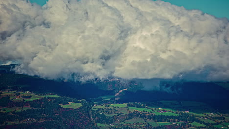 High-altitude-shot,-timelapse-of-cloudscape-humid-air-mixing-and-swelling,-alpine-clouds-above-peaceful-valley-during-spring-or-summer