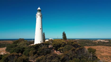 drone-shot-flying-close-by-wadjemup-lighthouse-on-Rottnest-Island-on-a-sunny-day-revealing-the-landscape-in-the-background,-Western-Australia