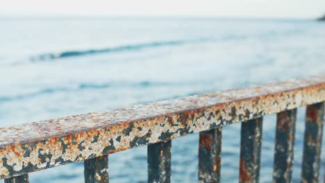 Female-putting-hands-on-rusted-metal-railing-on-waterfront,-depression-concept