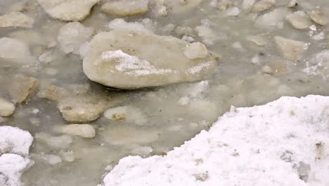 close-up-shot-of-a-pile-of-translucent-ice-chunks-sitting-on-a-bed-of-white-snow