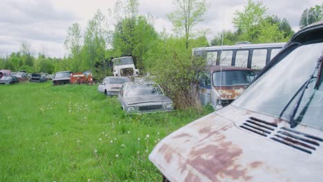 Camera-pulling-away-and-revealing-a-bunch-of-abandoned-cars-sitting-in-the-grass-rusting-away
