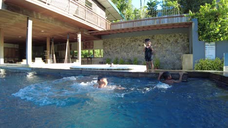 Kinder-Spielen-Am-Swimmingpool,-Indem-Sie-Sich-Gegenseitig-Schubsen-Und-Ins-Wasser-Fallen,-Dynamisches-Handheld