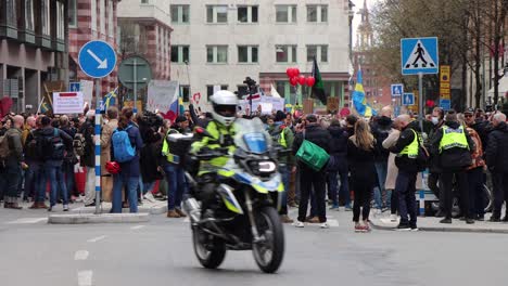 Static-shot-of-Police-on-motorcycle-driving-by-protesters-in-Stockholm
