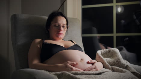 Baby-moving-in-the-womb,-pregnant-woman-relaxing-at-night