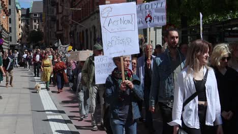 People-march-with-signs-at-climate-protest-rally-in-Sweden,-slo-mo