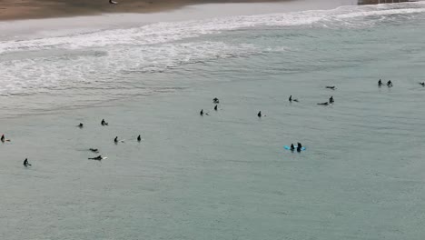 Toma-Aérea-De-Drones-De-Surfistas-En-Trajes-De-Neopreno-Esperando-Olas-Para-Surfear