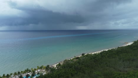 Cozumel-coastline-with-approaching-storm,-dark-clouds-over-turquoise-sea,-tropical-beachside,-aerial-view