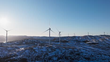 Motionless-Wind-Turbines-On-Snow-covered-Landscape-At-Sunrise