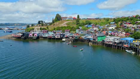 Drone-shot-of-boats-at-the-Palafitos-stilt-houses,-sunny-day-in-Castro-city,-Chile