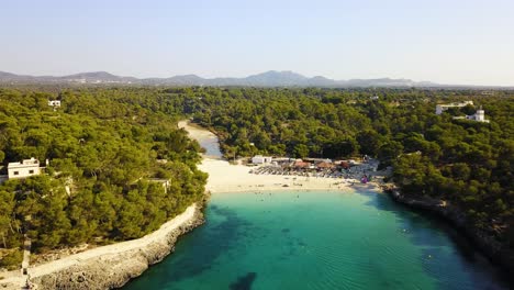 Approaching-drone-shot-of-the-beachfront-of-Calla-Mondrago,-a-natural-park-located-in-the-island-of-Mallorca,-in-Spain