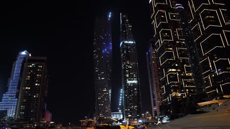 Dubai-Skyscrapers-and-Yachts-at-Night,-Dubai-Marina-Buildings-in-Lights